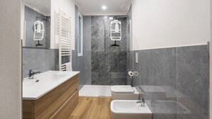 Un baño moderno con un espejo grande, dos lavamanos, un inodoro y una ducha.