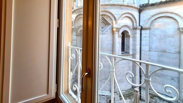 A window with a view of a courtyard featuring classical architecture with columns and arches. - Apartment 'La Chiocciola Nel Labirinto' with Balcony, Wi-Fi and Air Conditioning (Lucca)