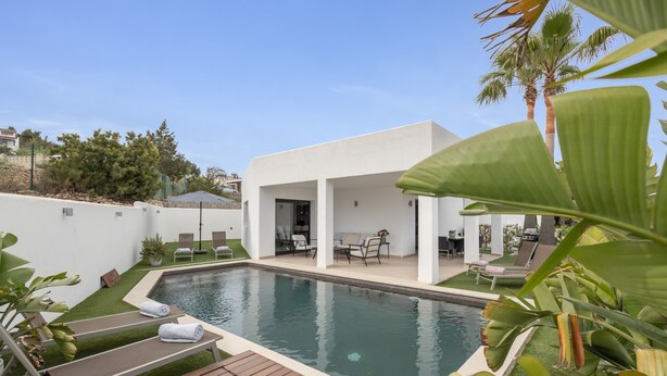 Ein moderner Poolbereich mit Holzterrasse, Liegestühlen und einer überdachten Sitzgelegenheit.