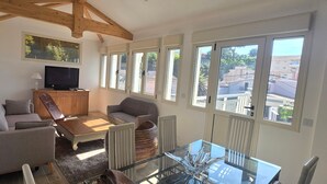 Un salon comprenant un canapé, un téléviseur, un meuble en bois et une table à manger avec des chaises.