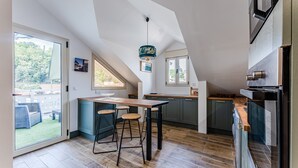 Une cuisine moderne avec un plan de travail en bois, des tabourets de bar et une grande fenêtre donnant sur un jardin.