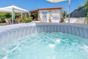 A hot tub with a tiled wall in the background, a covered seating area, and a stone wall with a tiled door. - Apartment 'Villa Dünya Ospitalità Siciliana' with Private Pool, Terrace and Air Conditioning (Noto Marina)