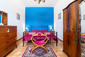 Ein Schlafzimmer mit Bett, Holzkommode und Stuhl.