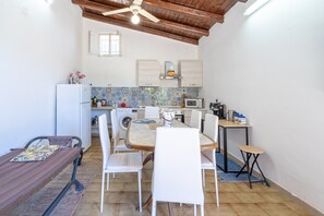 Une cuisine compacte comprenant un coin repas, un ventilateur de plafond, un lave-linge et un four à micro-ondes.