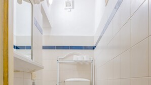 Un baño con lavamanos, inodoro y zona de ducha.