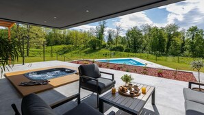A modern outdoor seating area with a hot tub, a pool, and a view of a lush green landscape. - Amazing home in Slunj (Slunj)