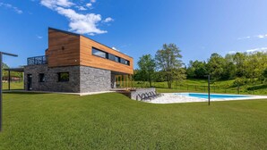 A modern two-story house with a stone facade and wooden upper levels, a swimming pool, and a well-maintained lawn. - Amazing home in Slunj (Slunj)
