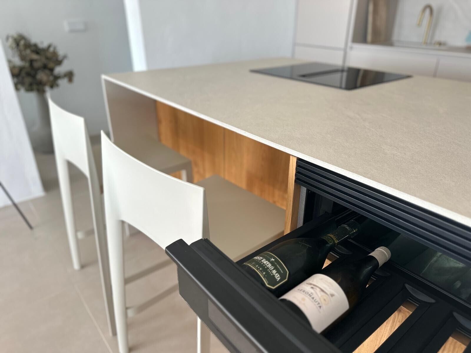 A kitchen with a built-in wine cooler, a white chair, and a wooden countertop.