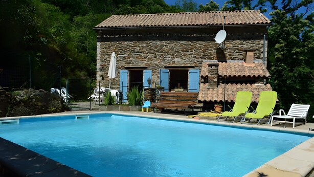 Ein Steinhaus mit Pool, Außenbereich und Satellitenschüssel.