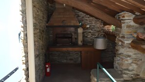 Ein Kamin aus Stein mit Schornstein, ein Feuerlöscher und eine rustikale Holzdecke.