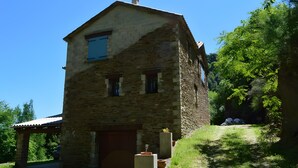 Ein Steinhaus mit Garage, einer überdachten Veranda und einem kleinen Garten mit Kübelpflanzen.