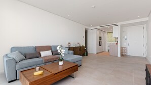 A modern living room with a sofa, coffee table, and a kitchen area in the background.