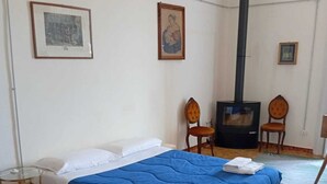 Ein Schlafzimmer mit einem Bett, Holzboden, Wandheizung und zwei gerahmten Bildern.