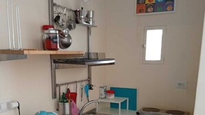 Eine kleine Küche mit Spüle, Wasserkocher und diversen Küchenutensilien.