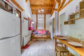 A narrow hallway with a wooden ceiling, a sofa, a wooden table, and a refrigerator.