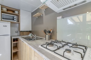 A kitchen with a microwave, refrigerator, sink, and gas stove.