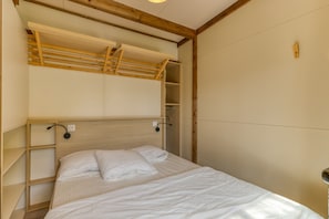A bedroom with a wooden headboard, a bed with white bedding, and built-in shelving.