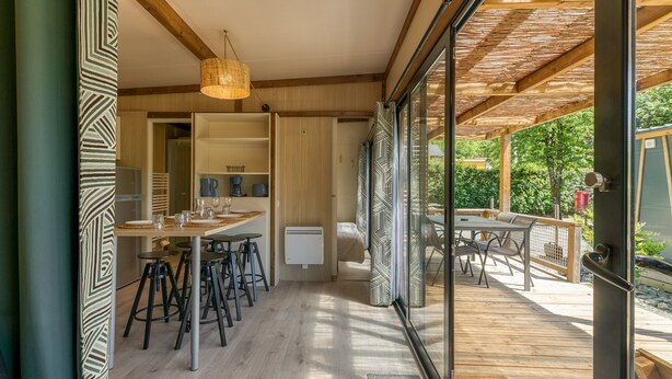 Een moderne keuken met een eetgedeelte, houten vloeren en uitzicht op het groen.