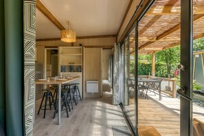 Une cuisine moderne avec un coin repas, un plancher en bois et une vue sur l’extérieur.