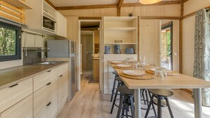 Een moderne keuken met houten kastjes, een ingebouwde magnetron en een eethoek met een tafel voor vier personen.