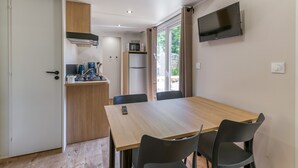 A compact kitchen with a microwave, refrigerator, and coffee maker. There is a dining table with chairs and a TV mounted on the wall. - Apartment 'Nest 29 N°25' with Mountain View, Wi-Fi and Air Conditioning (Vaulnaveys-le-Bas)