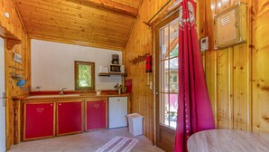 A wooden cabin interior with a kitchen, a dining area, and a window with curtains. - Apartment 'Chalet Violette' with Mountain View, Wi-Fi and Air Conditioning (Vaulnaveys-le-Bas)