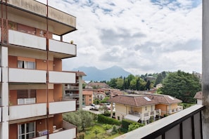 Un edificio residenziale a più piani con balconi, vista su una cittadina con case e montagne sullo sfondo.