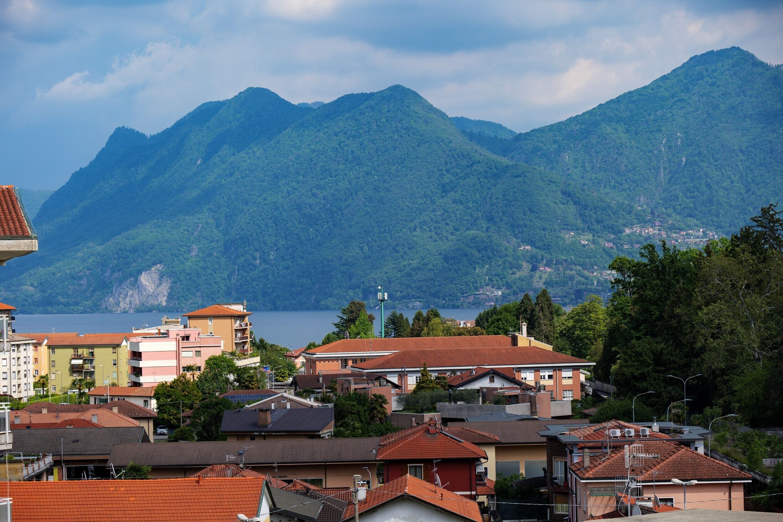 A coastal town with buildings, a mountain backdrop, and a body of water.