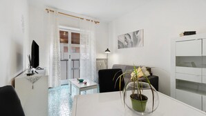 Un salon moderne comprenant une table à manger, un canapé, un téléviseur et une plante en pot.