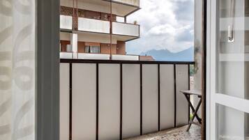 A balcony with a tiled floor, a metal table, and a view of a mountain range.
