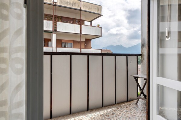 A balcony with a tiled floor, a metal table, and a view of a mountain range.
