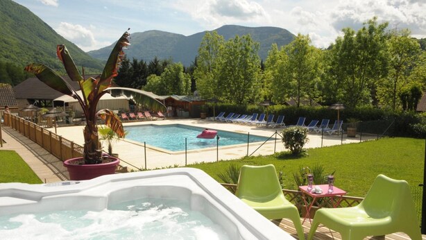 Ein Whirlpool, ein Schwimmbecken, Liegestühle und ein Berg im Hintergrund.