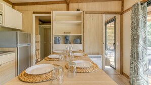 A modern kitchen with a built-in refrigerator, wooden cabinets, and a dining area with a table set for four.