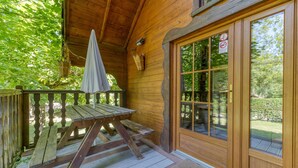 A wooden deck with a picnic table and umbrella, a glass door with a no smoking sign, and a view of greenery. - Apartment 'Narcisse' with Mountain View, Wi-Fi and Air Conditioning (Vaulnaveys-le-Bas)