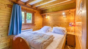 A wooden cabin room with a bed, a window, and a nightstand. - Apartment 'Narcisse' with Mountain View, Wi-Fi and Air Conditioning (Vaulnaveys-le-Bas)