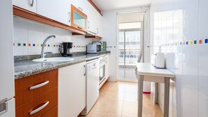 Une cuisine moderne avec des armoires blanches, un comptoir en granit, un four encastré et une machine à café.