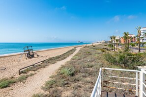 A beach with a bicycle, a wooden walkway, and buildings in the background.