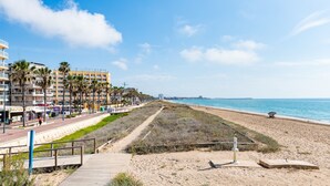 Une promenade en bord de mer, avec une jetée, des palmiers et un immeuble doté de balcons.