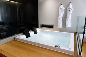 A modern bathroom with a large bathtub, a glass shower enclosure, and two white towels hanging on hooks. - Bed and Breakfast 'Zoe Luxury Suites - Deluxe 03' with Sea View, Wi-Fi and Air Conditioning (Catania)