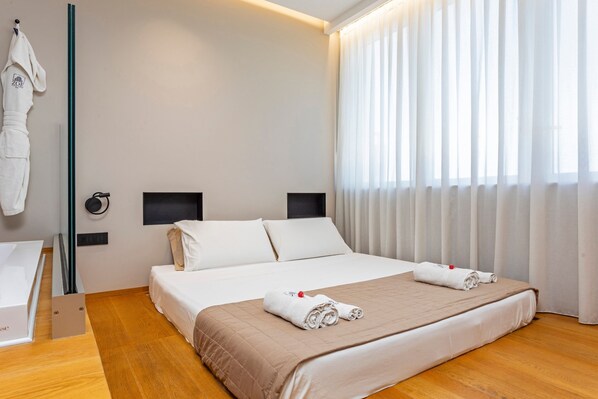Ein Hotelzimmer mit einem Bett, einem Nachttisch, einem Spiegel und einem Vorhangfenster.