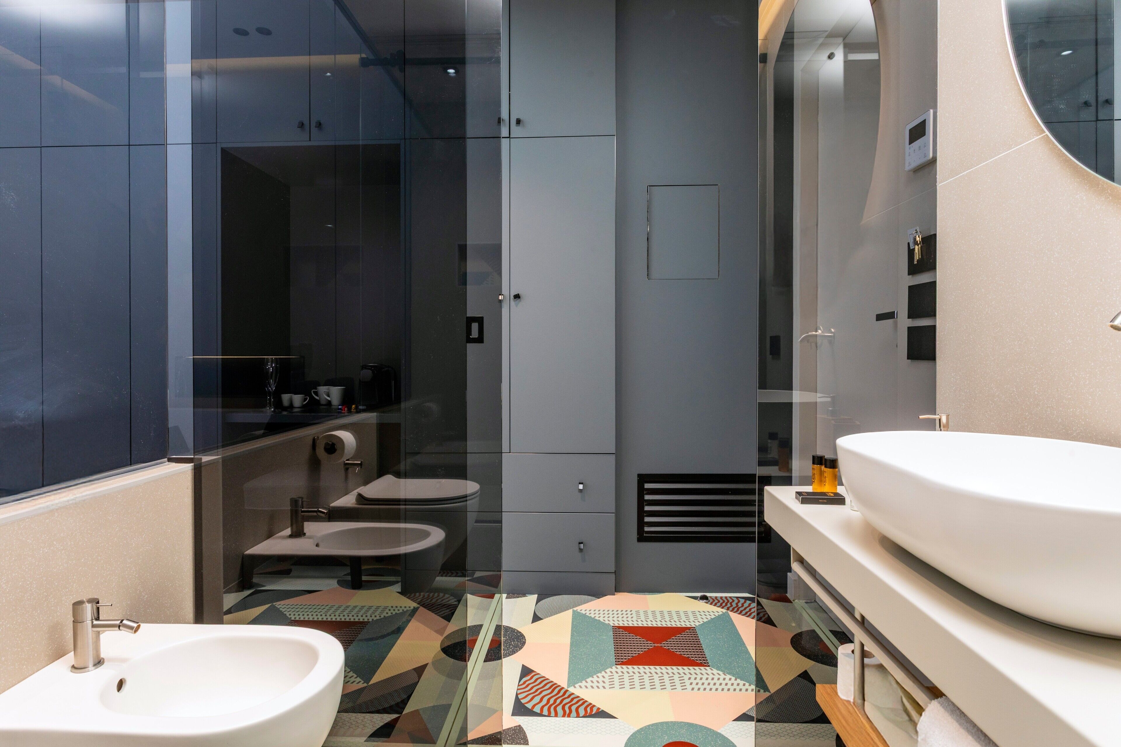 Un baño moderno con un espejo grande, dos lavabos, un inodoro y una ducha.