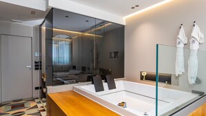 A modern bathroom with a large glass-enclosed bathtub, a wooden vanity, and a mirror with towels. - Bed and Breakfast 'Zoe Luxury Suites - Deluxe 03' with Sea View, Wi-Fi and Air Conditioning (Catania)