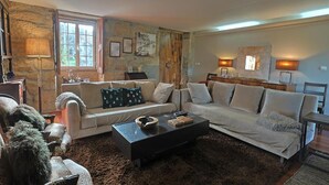 Un salon avec deux canapés, une table basse et un mur en pierre.