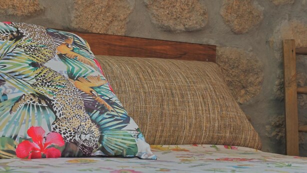 Un lit avec une couvre-lit à motifs floraux, un coussin à imprimé léopard et un mur à texture.