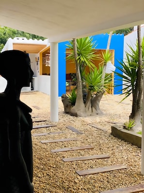 Ein Innenhof mit einem weißen Gebäude, Palmen und einer Statue.