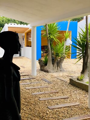 A courtyard with a white structure, palm trees, and a statue.