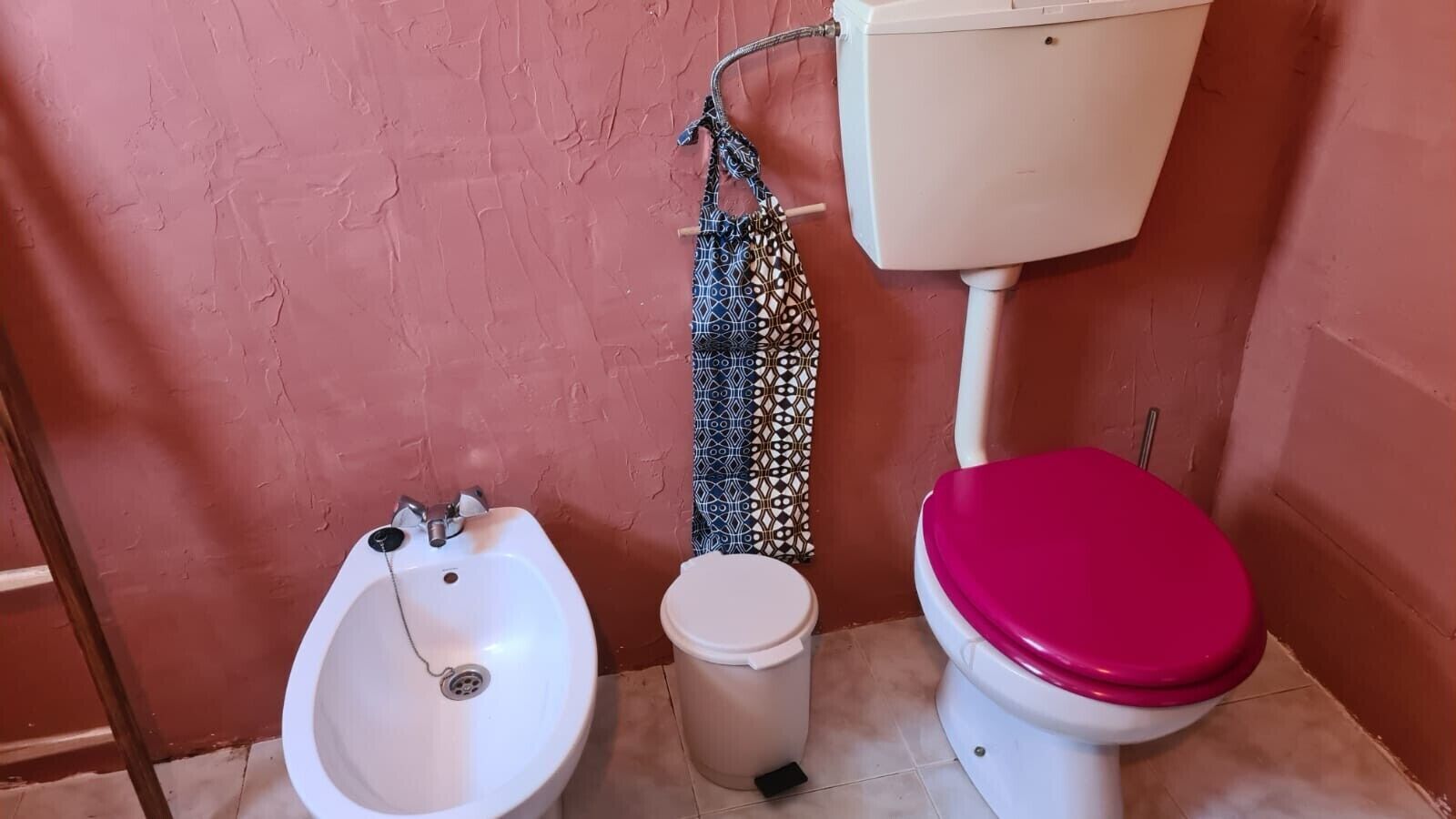 Kylpyhuone, jossa on bidee, wc ja kuviollinen verho.