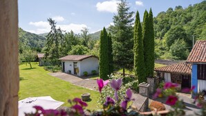A rural landscape with a white building, a stone structure, and tall trees. - Room 'Carbayu' with Mountain View, Shared Garden and Wi-Fi (Con)