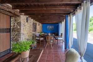 A covered outdoor seating area with stone walls, wooden furniture, and potted plants. - Room 'Araucaria' with Mountain View, Shared Garden and Wi-Fi (Con)