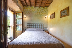 Une chambre à coucher avec un lit, une fenêtre, une porte et un mur orné d’un motif floral.